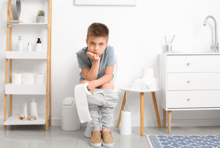 Kind sitzt genervt auf der Toilette.